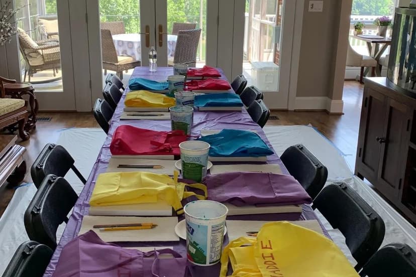 Indoor paint party table with colorful aprons and canvas supplies