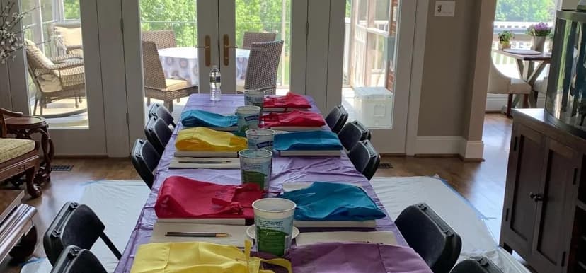 Indoor paint party table with colorful aprons and canvas supplies