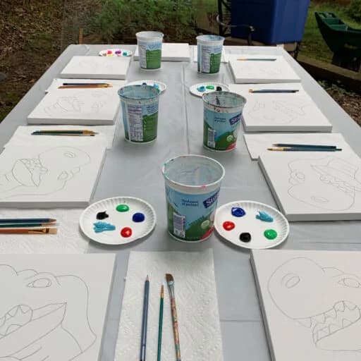 Outdoor table set with dinosaur canvases for a kids painting party in Frisco, TX