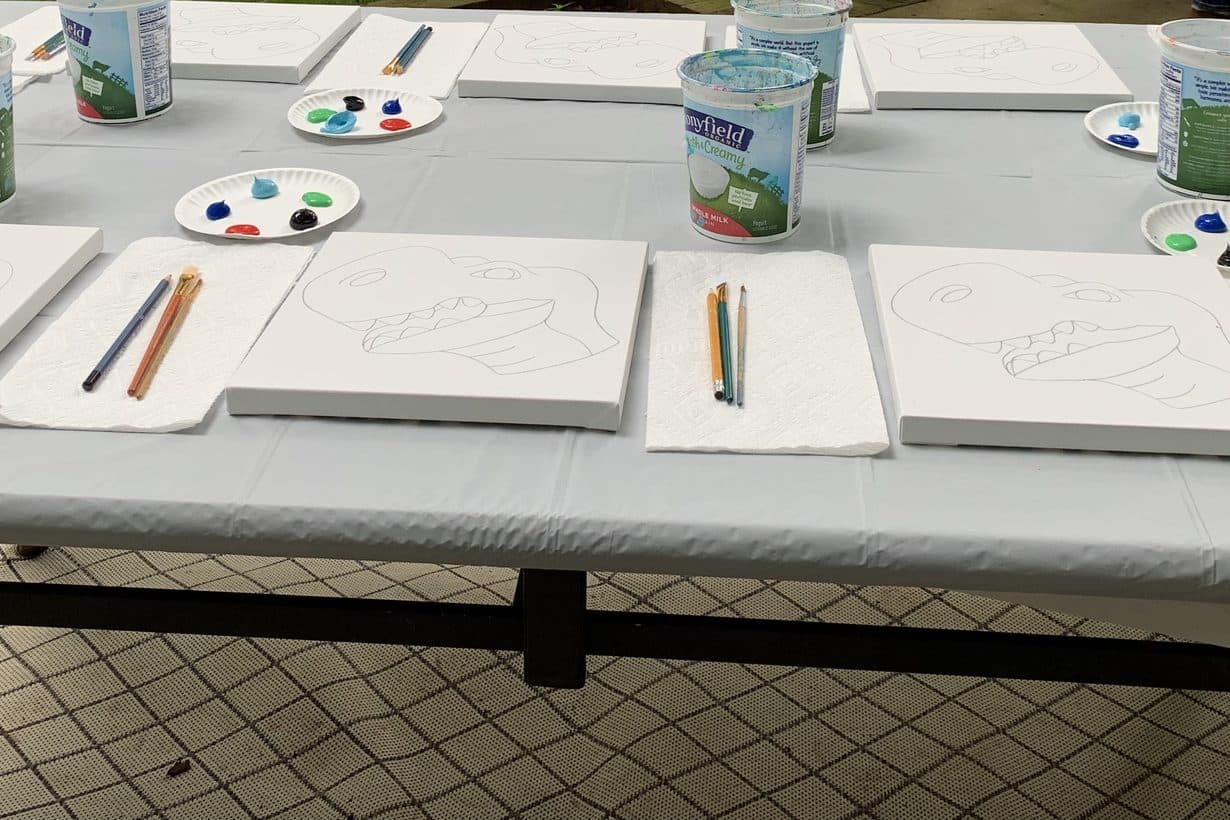 Outdoor paint party table set up on a patio with pre-sketched canvases and supplies