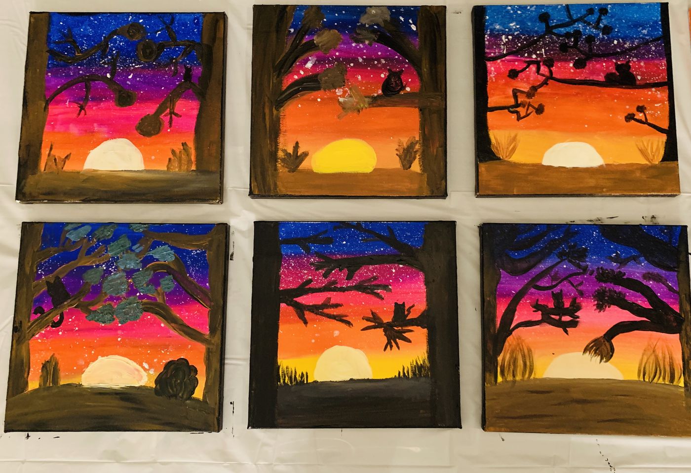 Six finished sunset canvas paintings lined up after a kids paint party