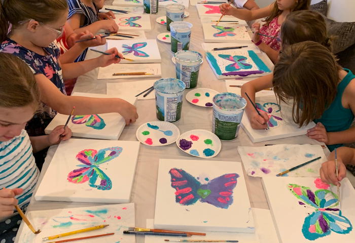 Kids painting colorful butterfly canvases at a paint party