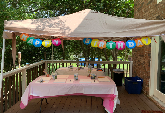 Outdoor deck paint party table with Happy Birthday banner and canvases