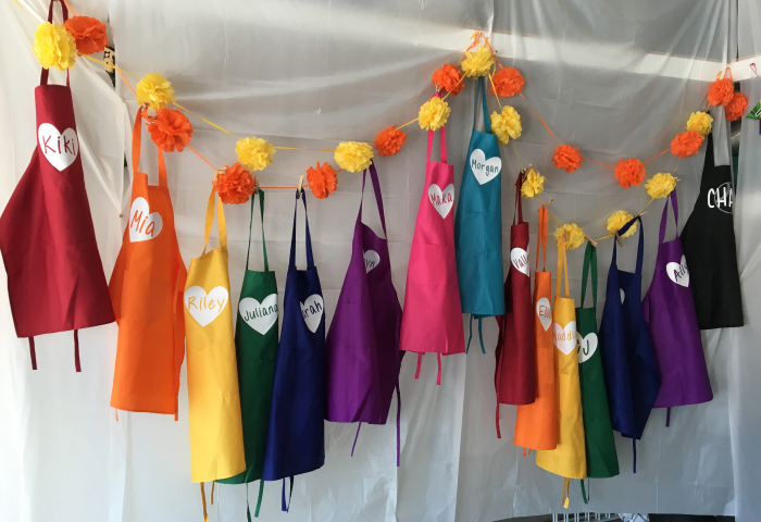 Colorful personalized aprons with pom pom garland at paint party